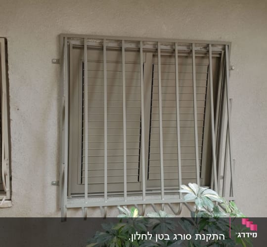 חלון עם סורגים ותריסים סגורים על קיר חיצוני